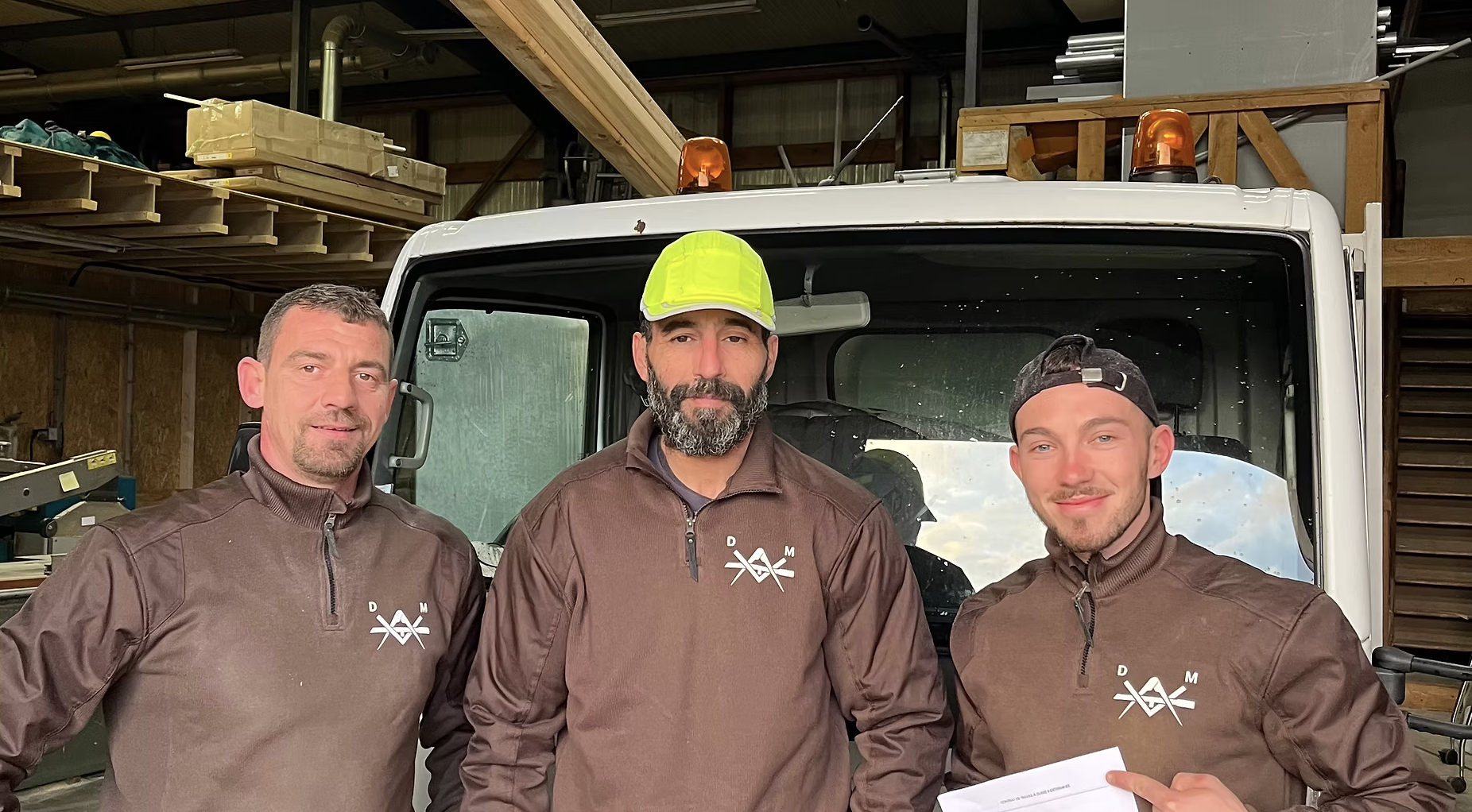 Maël et l'équipe DM Menuiserie Charpente en uniforme devant leur camion de chantier